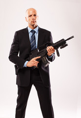 Serious tall man in a suit with a rifle