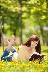 Young woman reading a book in the park with flowers