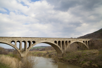 Fototapeta na wymiar Old stone middle age bridge in Bulgaria, against a cloudy sky
