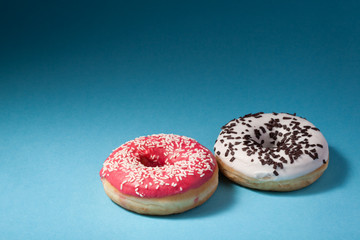 two donuts with red and white icing isolated on blue background