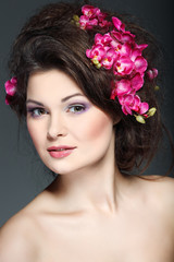 Naklejka premium beautiful brunette with pink orchids in hairs, cosmetics