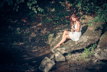 girl with book onbank of small river