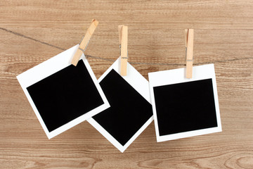 Photo papers hanging on the clothesline on wooden background