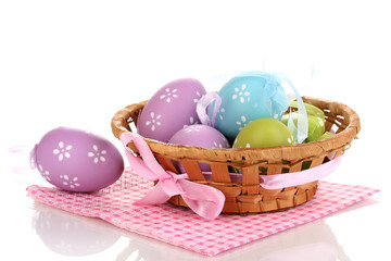 Colorful easter eggs in basket on napkin isolated on white