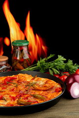 Tasty pepperoni pizza in pan with vegetables on flame