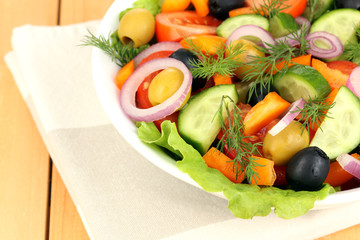 Fresh salad in plate on wooden table