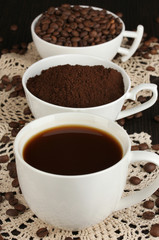 Different types of coffee in three cups on wooden table