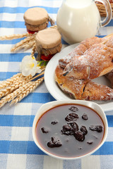 Taste croissants, milk and jam, on tablecloth.