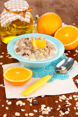 Useful oatmeal in bowl with fruit on wooden table close-up