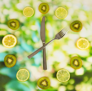 Clock made of kiwi, lime and lemon slices, on bright background
