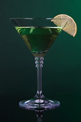 Green cocktail with lime on dark green background
