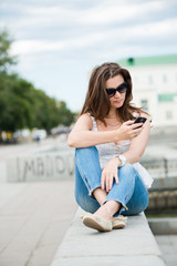 Outdoor portrait of young woman with phone
