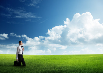 young business man wolking at the field of grass