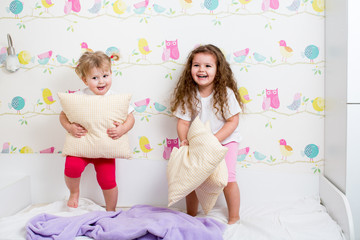 children sisters playing on the bed indoors - Powered by Adobe