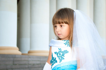 Little bride. A girl in a lush white and blue wedding dress and