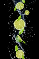 Wall murals Best sellers in the kitchen Limes in water splash, isolated on black background