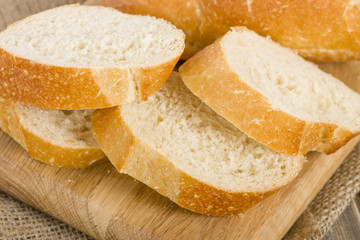 Crusty slices of white bread on a wooden chopping board.