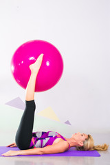 Fototapeta na wymiar beautiful pilates instructor with pink ball and purple yoga mat