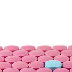 Blue pill between pink pills on white background