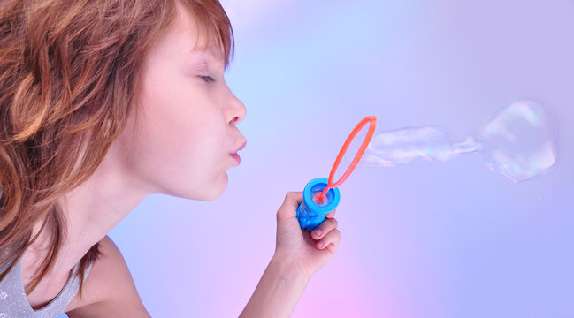 girl  blowing soap bubbles against bright background