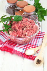 Bowl of raw ground meat with spices on wooden table