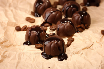 Chocolate candies and coffee beans, on beige paper background