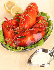 Red lobster on platter with vegetables on wooden table close-up