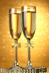 Two glasses of champagne on bright background with lights