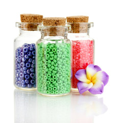 Little bottles full with colorful beads isolated on white