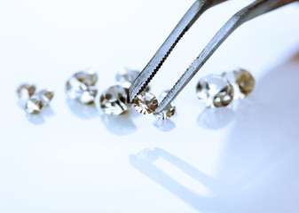 Beautiful shining crystal (diamond) in the tweezers, isolated