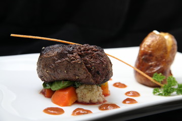 Tenderloin steak portion with potato on black background
