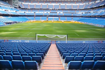 Fotobehang Leeg voetbalstadion met blauwe stoelen, opgerolde poorten © Pavel Losevsky