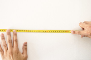Closeup of a measuring tape in wall white