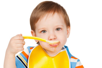 Boy eats with a spoon puree, isolated on white