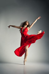 Fototapeta premium Baletnica ubrana w czerwoną sukienkę na szarym