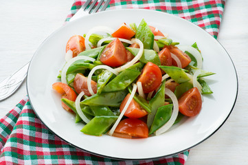 Fresh snow peas and tomato salad on plate