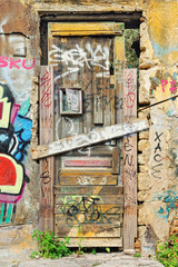 Weathered barricaded door and heavy graffiti on a abandoned hous