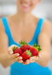 Closeup on smiling young woman giving strawberries