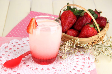 Delicious strawberry yogurt in glass on wooden table close-up