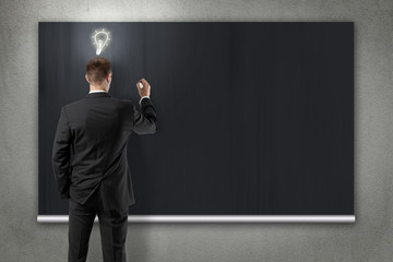 businessman is writing down ideas on blackboard