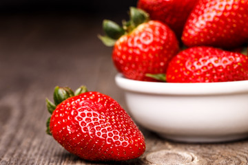 Strawberries in white plate on the old wooden table. 