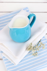 Blue jug with milk on napkin on wooden picnic table close-up