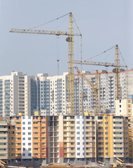 Fototapeta na wymiar Yellow hoisting tower cranes construction city buildings