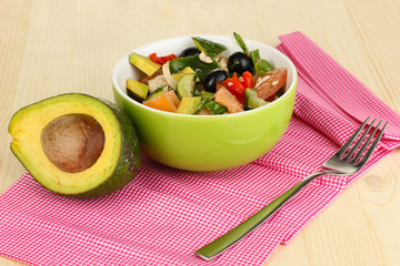 Tasty avocado salad in bowl  on wooden table close-up
