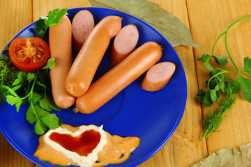 Sausage, greens, tomato on plate on wooden table