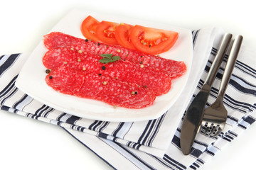 Tasty salami on plate on  napkin isolated on white