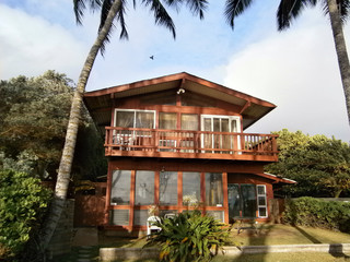 Red Beach House with tall coconut trees on Oahu, Hawaii