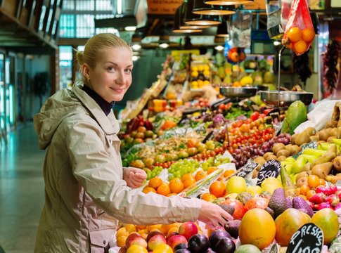 Young  woman choosing fresh fruits on market