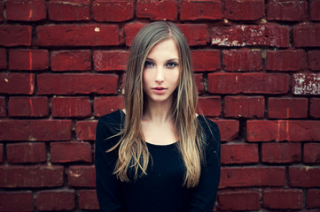 beautiful girl on a background of an old brick wall in red