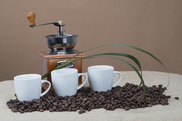 Tres tazas de café y molinillo para moler los granos.